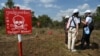 FILE - Ukraine deminers talk to a Cambodian deminer near a warning sign during a technical training session on demining technologies in Battambang province on Jan. 19, 2023.