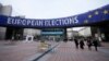 FILE - People walk under a banner advertising the European elections outside the European Parliament in Brussels, on Jan. 24, 2024. 