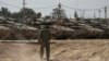 Israeli soldiers work on tanks at a staging ground near the border with the Gaza Strip, in southern Israel, April 11, 2024.