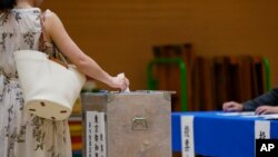 A woman casts her vote at a polling place for Tokyo's governor election in Tokyo, July 7, 2024. 