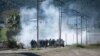 French gendarmes stand amid tear gas smoke as clashes occur with pro-independence protesters during the removal of a roadblock on Paul-Emile Victor avenue in Dumbea on the French Pacific territory of New Caledonia, June 24, 2024. 