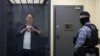 Wall Street Journal reporter Evan Gershkovich, who is in custody on espionage charges, makes a heart-shaped gesture inside an enclosure for defendants before a court hearing in Moscow, April 23, 2024.
