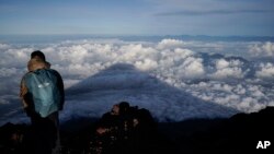 FILE - The shadow of Mount Fuji is cast on clouds hanging below the summit Aug. 27, 2019, in Japan. 