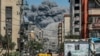 A cloud of smoke erupts down the road from an explosion in Nuseirat in the central Gaza Strip on April 17, 2024.
