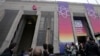 A protestor from Greenpeace hangs on the building with a banner during arrivals for a Nuclear Energy Summit at the Expo in Brussels, March 21, 2024.