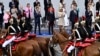 France's Prime Minister Gabriel Attal, President Emmanuel Macron and first lady Brigitte Macron applaud as the Cavalry Regiment of the French Republican Guard rides past during the Bastille Day military parade in Paris, July 14, 2024. 