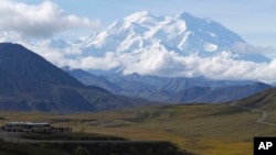 FILE - Sightseeing buses and tourists are seen at a pullout popular for taking in views of North America's tallest peak, Denali, in Denali National Park and Preserve, Alaska, Aug. 26, 2016.
