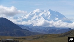 FILE - Sightseeing buses and tourists are seen at a pullout popular for taking in views of North America's tallest peak, Denali, in Denali National Park and Preserve, Alaska, Aug. 26, 2016.