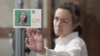 FILE - Russian-American journalist for Radio Free Europe/Radio Liberty Alsu Kurmasheva holds a card reading "She's expected home" as she attends a court hearing in Kazan, Russia, April 1, 2024. 