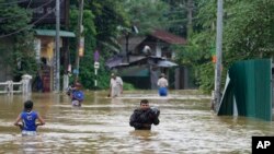 People wade through flood waters in Kelaniya, a suburb of Colombo, Sri Lanka, June 3, 2024.