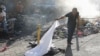 A person lifts a sheet to look at the identity of a body lying on the ground after an overnight shooting in the Petion Ville neighborhood of Port-au-Prince, Haiti, March 18, 2024.
