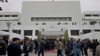 Members of the media and security personnel gather at the main entrance of the National Assembly building, as the opening session of parliament commences, in Islamabad, Pakistan, Feb. 29, 2024. 