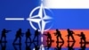 Foto ilustrasi yang menggambarkan figur tentara ditampilkan di depan bendera Rusia dan NATO. Foto diambil pada 13 Februari 2022. (Foto: Reuters/Dado Ruvic)