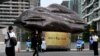 Morning commuters walk past a giant inflatable depicting a piece of coal erected by Greenpeace outside Australian energy company AGL in Melbourne on March 28, 2022. 