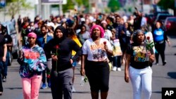 Des gens marchent sur les lieux d'une fusillade dans un supermarché de Buffalo, N.Y., le 15 mai 2022.