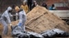 Des hommes portant des équipements de protection exhument les corps de civils tués pendant l'occupation russe à Bucha, à la périphérie de Kiev, Ukraine, le 13 avril 2022 (AP). 