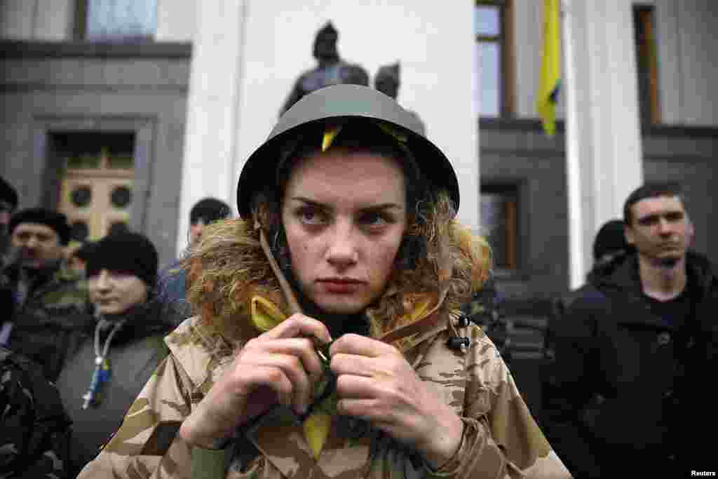 Demonstran anti-Yanukovych mengencangkan helmnya ketika berjaga-jaga di depan gedung parlemen bersama rekan-rekannya di Kyiv, 27 Februari 2014.