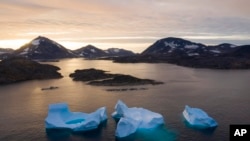 FILE - Large icebergs float away as the sun rises near Kulusuk, Greenland, Aug. 16, 2019. 