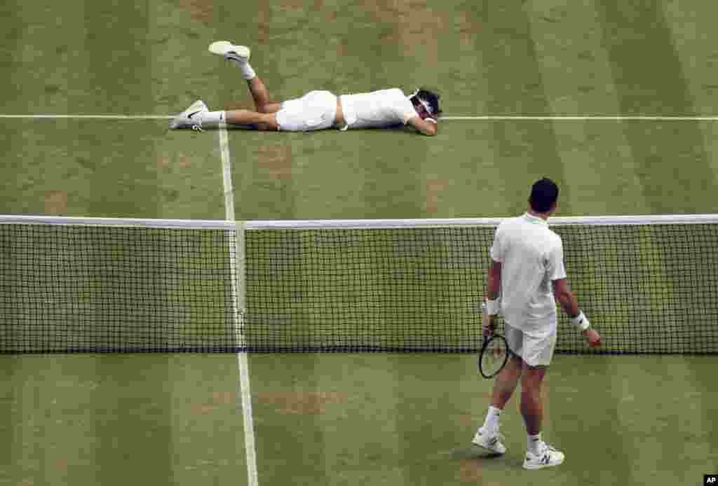 Roger Federer of Switzerland, top, falls over during his men's semifinal singles match against Milos Raonic of Canada on day 12 of the Wimbledon Tennis Championships in London. Federer ended up losing the match.