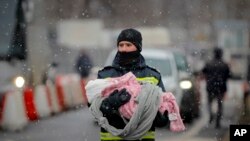 在罗马尼亚边境城站锡雷特，一名消防队员抱着从邻国乌克兰逃出来的一名难民的婴儿。(2022年3月7日)