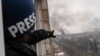 Press photographer Evgeniy Maloletka points at smoke rising after an airstrike on a maternity hospital, in Mariupol, Ukraine, March 9, 2022.