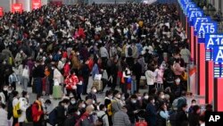 中国交通压力最大，一年一度的“春运”在如同海啸般蔓延的新冠感染爆发中拉开帷幕。广东深圳南站大厅内，旅客们人们带着口罩和行李，熙熙攘攘挤满大厅，等待买票和登车。本照片由新华社发布，美联社提供。