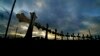 FILE - A truck passes crosses placed along the highway to honor the victims killed in the recent school shooting at Robb Elementary School, in Uvalde, Texas, June 6, 2022.
