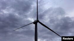 FILE - A worker stands atop a wind turbine during a routine inspection at the Infigen Energy wind farm located on the hills surrounding Lake George, 50 km north of the Australian capital city of Canberra, May 13, 2013.