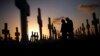 FILE - A couple grieves at a grave in a cemetery Coral Gables, Florida, Feb. 16, 2008. A new study shows that suicide rates in the U.S. jumped 24 percent between 1999 and 2014.