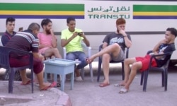 Young men are seen at a bus stop cafe in Tunis. Unemployment reaches 30 percent in some parts of Tunisia. (L. Bryant/VOA)