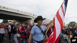 Foto Achiv: Yon migran pote drapo Ameriken an pandan lap rale yon malet nan mitan yon karavan migran kap kite Tapachula nan eta Chiapas, Meksik, bone 6 Jyen 2022. 