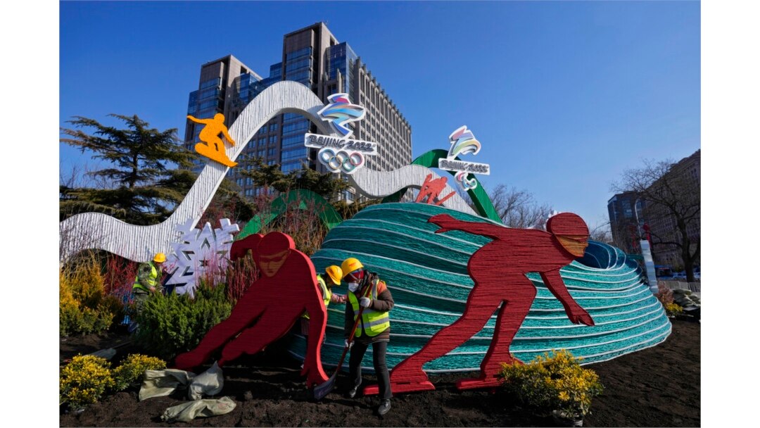 Workers wearing face masks to help protect from the coronavirus set up a decoration for the Winter Olympic Games in Beijing, Jan. 16, 2022.
