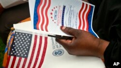 Une immigrante d'origine gambienne tient un drapeau lors d'une cérémonie de naturalisation de 50 nouveaux citoyens issus de 24 pays, le vendredi 16 juin 2017, à New York.