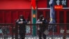 FILE - Security guards browse their smartphones near shuttered business shops in Beijing, China, Feb. 23, 2020.