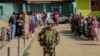 An Indian soldier stands guard as people wait to cast votes at a polling booth in Shadipora, India-administered Kashmir, on May 20, 2024. As the nation holds its national elections, India is cited as an example of the sharp curtailing of freedom of expression around the world.