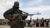FILE - A member of the Taliban and other people stand at the site during the execution of three men in Ghazni Province, Afghanistan, April 18, 2015. On Feb. 22, 2024, Taliban authorities publicly executed two men convicted of murder in separate cases.