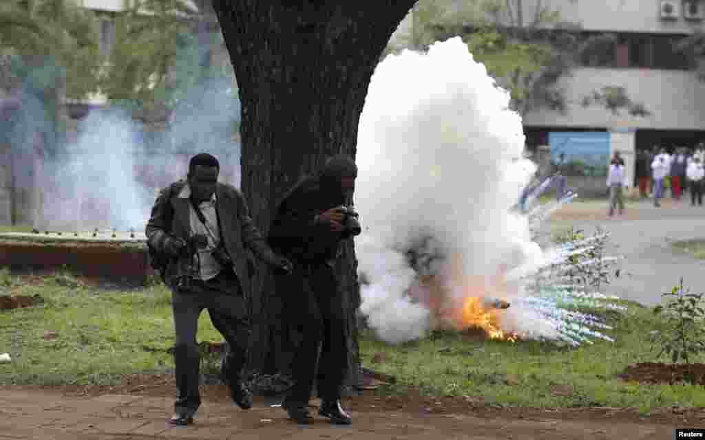 Dua wartawan foto menghindar dari gas air mata yang dilemparkan oleh polisi anti huru-hara untuk membubarkan demonstrasi mahasiswa di Nairobi, Kenya.&nbsp;