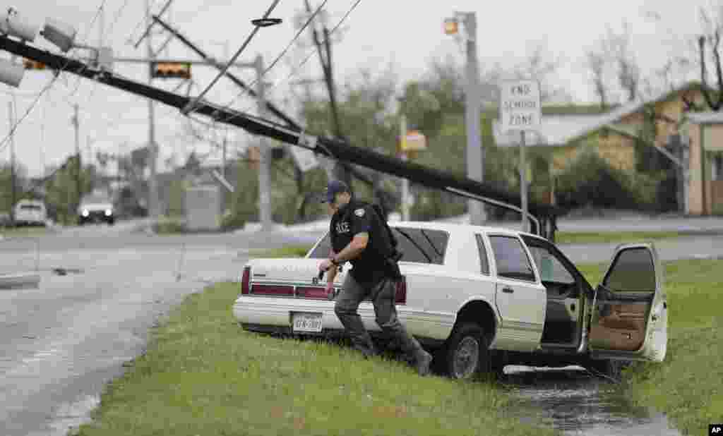 A police officer checks an abandoned vehicle as the last of Hurricane Harvey passes the area in Rockport, Texas, Aug. 26, 2017.