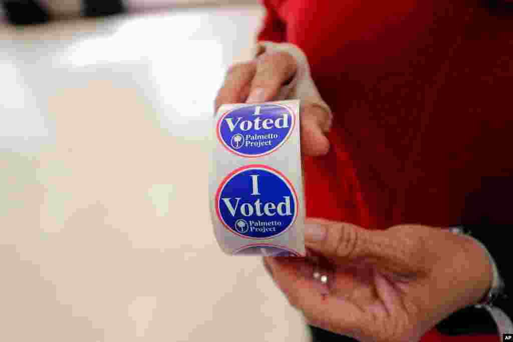 Polling manager Diana Belton shows a roll of voting stickers as people arrive to vote in the Democratic presidential primary in Hopkins, S.C., Feb. 29, 2020.