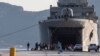 Des migrants attendent devant un navire militaire après leur débarquement dans le port d'Elefsina, près d'Athènes, le samedi 2 novembre 2019. (AP)
