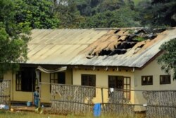 FILE - A woman stands outside a damaged school dormitory after it was set on fire, in Bafut, in the North West English-speaking region of Cameroon, Nov. 15, 2017.