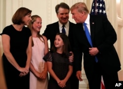 FILE - President Donald Trump talks with Judge Brett Kavanaugh his Supreme Court nominee, and his family in the East Room of the White House, July 9, 2018.