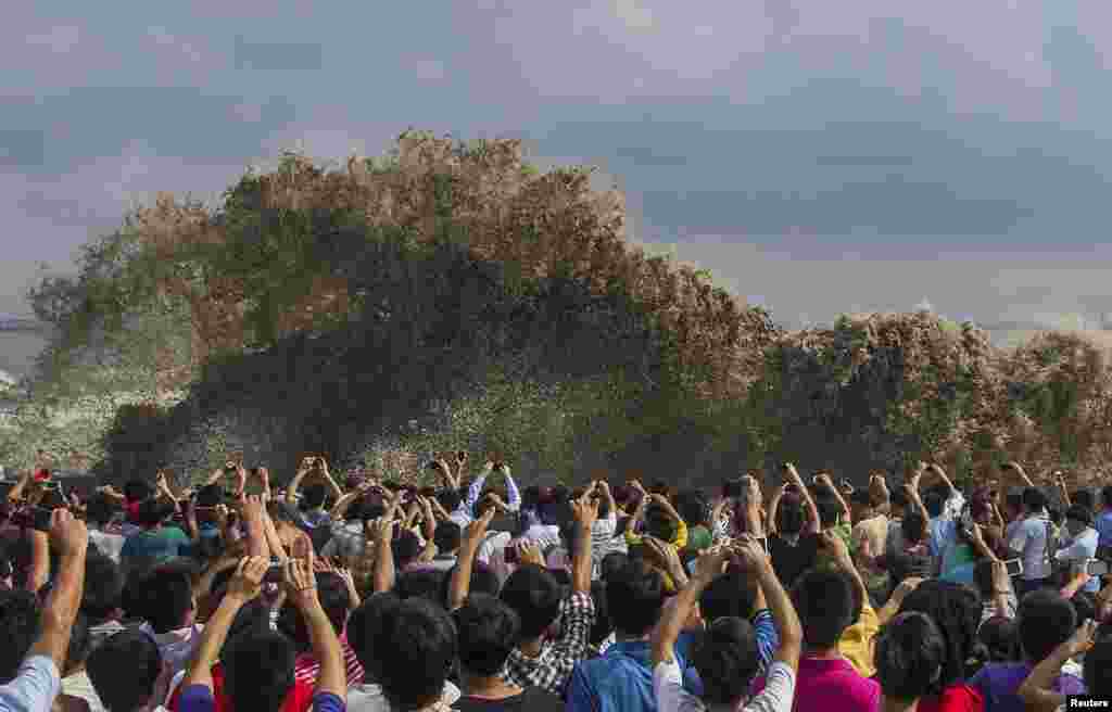 Pengunjung mengambil foto gelombang pasang akibat topan Usagi di Hangzhou, provinsi Zhejiang, China, 22 September 2013. 