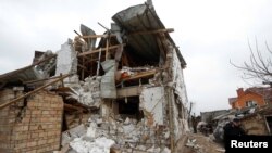 Місцеві жителі прибирають уламки біля будинку свого сусіда, який постраждав від російського військового удару під час нападу Росії на Україну, село Глеваха під Києвом, 26 січня 2023 року. REUTERS/Valentyn Ogirenko