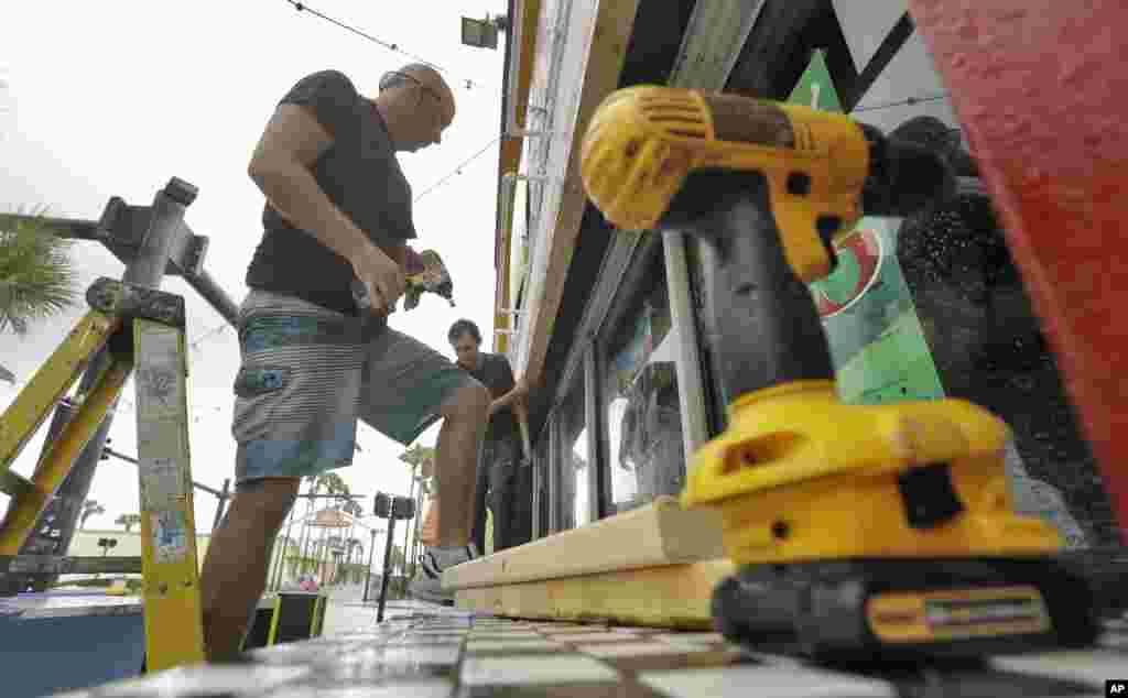Michael Blackman, left, and Sam Titus board up a bar a few blocks off the beach on October 6, 2016, in Daytona Beach, Fla. The bar is planning on staying open during Matthew.