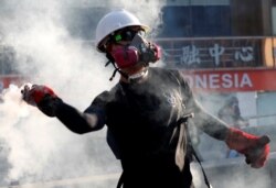 FILE - A protester throws a tear gas canister back at the police during a demonstration in support of the city-wide strike and to call for democratic reforms in Hong Kong, China, Aug. 5, 2019.