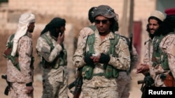 A Syrian Democratic Forces fighter uses a mobile phone as he stands with his fellow fighters in the town of Hisha, Syria, after they took control of the area from Islamic State militants, Nov. 14, 2016. 