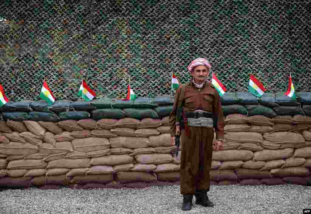Seorang pejuang Kurdi Peshmerga berdiri di depan deretan bendera Kurdi pada posisi di garis depan distrik Gwer, 40 kilometer selatan Arbil, ibukota daerah otonom Kurdi di Irak Utara, sementara mereka terus bertempur melawan kelompok pejuang Negara Islam (ISIS) 