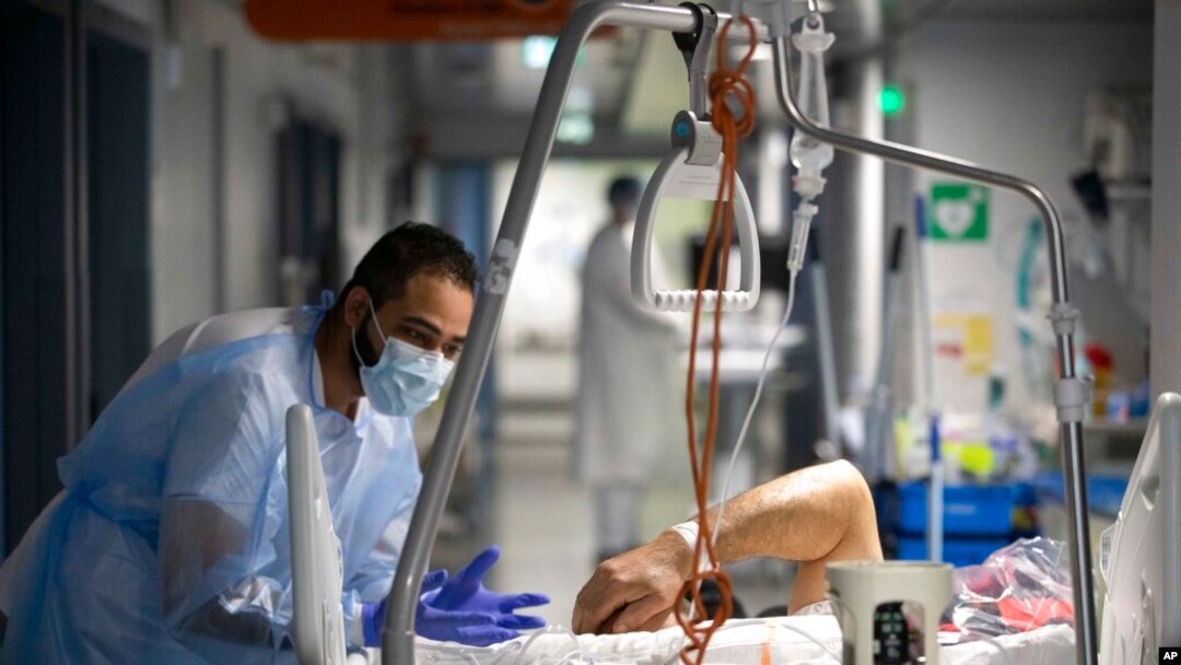 A medical staff member speaks with a COVID-19 patient in the infectious disease ward of the Strasbourg University Hospital, eastern France, Jan. 13, 2022.