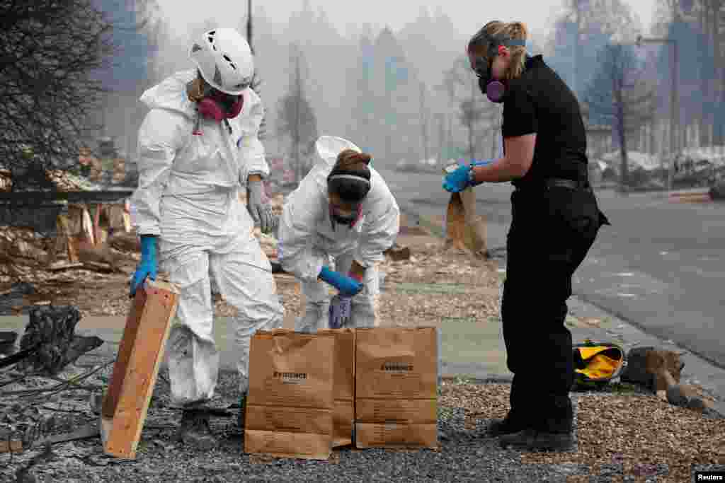 (L-R) Forensic anthropologists Kyra Stull and Tatiana Vlemincq work with San Mateo County Deputy Coroner Elizabeth Ortiz to recover human remains from a trailer home destroyed by the Camp Fire in Paradise, California, U.S., November 17, 2018. 